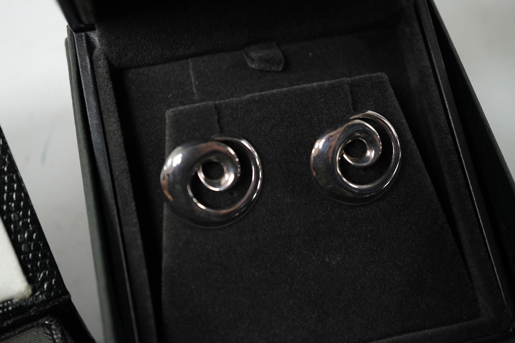 A modern pair of Georg Jensen 925S cufflinks, of swirling form, design no. 443, with original Georg Jensen box, 20mm, together with a modern pair of silver fish cufflinks by Sarah Jones, London, 1993/94. Condition fair a